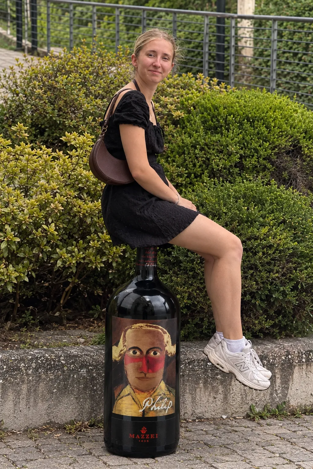 Marie K. sitzt auf einer großen Flasche Mazzei Philip